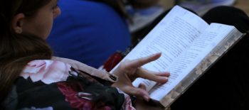 Дівчина тримає в руках відкриту книгу і читає