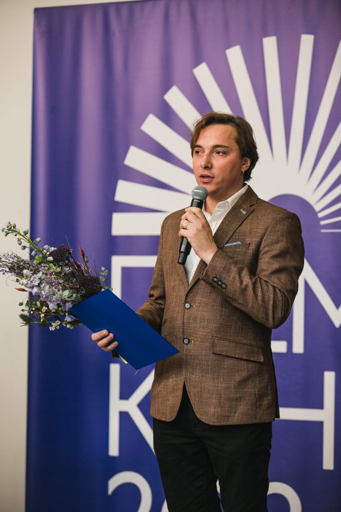 Андрій Любка виступає на нагородженні лауреатів Премії Конрада із квітами та мікрофоном у руках.
