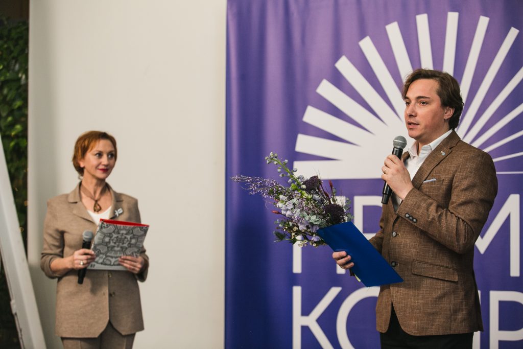 Андрій Любка виступає на нагородженні лауреатів Премії Конрада із квітами та мікрофоном у руках.