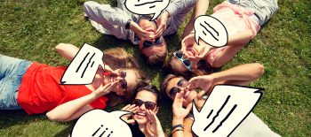 group of smiling friends lying on grass outdoors