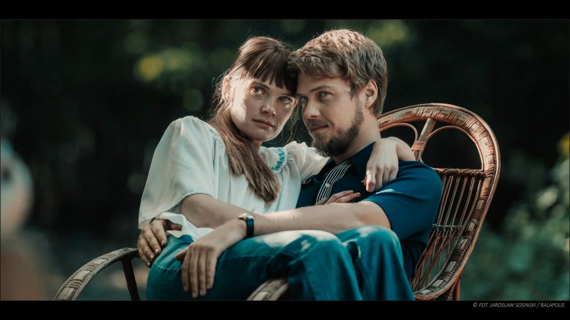 Na fotografii z filmu Simona Kossak je dvojice mladých lidí: herecká představitelka přírodovědkyně Simony Kossak v podání herečky Sandry Drzymalské, sedí na klíně svému filmovému partnerovi Lechu Wilczkovi v podání herce Jakuba Gierszała