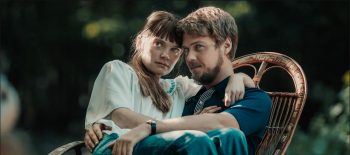 Na fotografii z filmu Simona Kossak je dvojice mladých lidí: herecká představitelka přírodovědkyně Simony Kossak v podání herečky Sandry Drzymalské, sedí na klíně svému filmovému partnerovi Lechu Wilczkovi v podání herce Jakuba Gierszała
