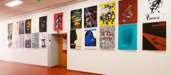 Na fotografii je galerie na Fakultě multimediálních komunikací Univerzity Tomáše Bati ve Zlíně, a na stěně jsou umístěny studentské plakáty.