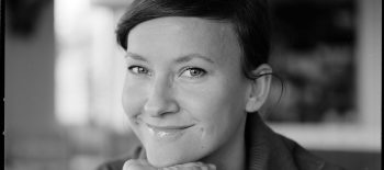 Na černobílé fotografii je usměvavá tmavovlasá žena, spisovatelka Ilona Wiśniewska