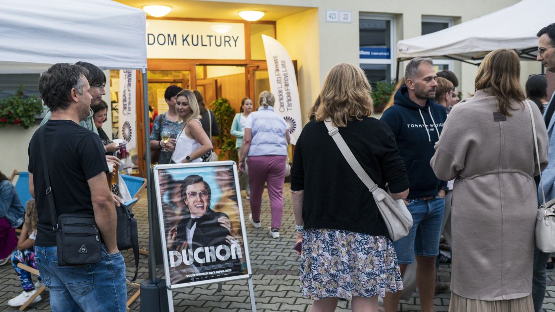 Na fotografii je shluk lidí před kulturním domem v Těrlicku, na zemi je strojan s filmovým plakátem.