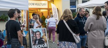 Na fotografii je shluk lidí před kulturním domem v Těrlicku, na zemi je strojan s filmovým plakátem.