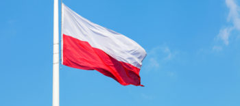Polish national flag waving on the wind against blue cloudy sky
