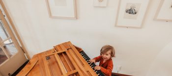 Ein kleiner Junge sitzt spielend am Klavier und lacht in die Kamera © Mozarthaus Vienna / Foto: Paul Bauer